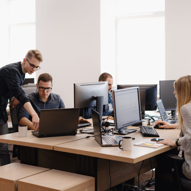 Full concentration at work. Group of young business people working and communicating while sitting at the office desk together with colleagues sitting in the background